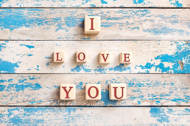 木製の背景に文字が書かれた木製の立方体を使用して書かれた「愛しています」。バレンタインデーのポストカード。