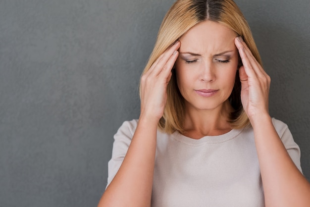 I need some painkillers. Depressed mature woman touching forehead and keeping eyes closed