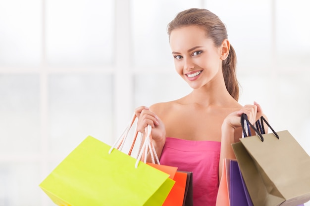 I need some retail therapy. Attractive young woman holding shopping bags and smiling at camera