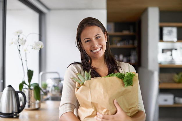 Я покупаю только органические продукты. Молодая женщина стоит на кухне и держит сумку с продуктами.