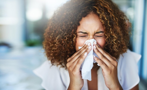 I think Im going to the doctor later Shot of a frustrated businesswoman using a tissue to sneeze in while being seated in the office