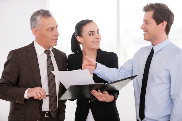 I think it is a good deal. Three confident business people discussing something while woman holding documents