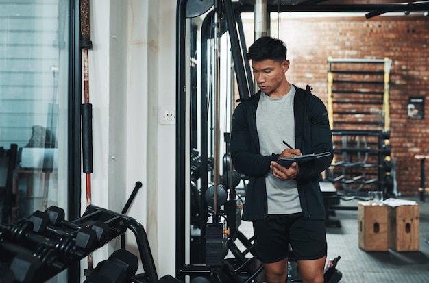 I think were going to need one more of these Cropped shot of a handsome young male fitness instructor inspecting exercise equipment while working in a gym