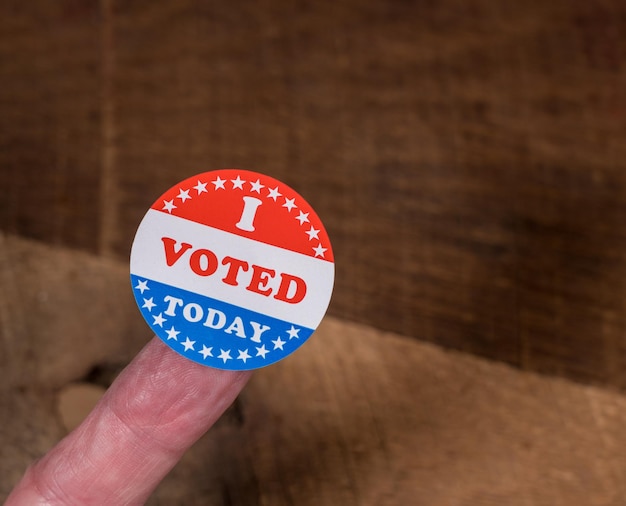 Photo i voted today sticker on senior caucasian mans finger on rustic rural wooden table