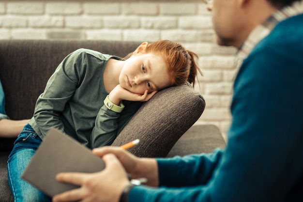 休みたい。疲れを感じながらソファに寄りかかって悲しい不幸な少女