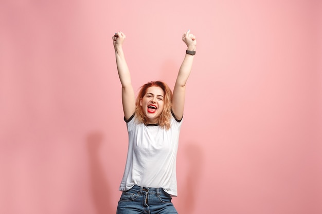 Foto ho vinto. donna felice di successo di conquista che celebra essere un vincitore. immagine dinamica del modello femminile caucasico su sfondo rosa studio. vittoria, concetto di gioia. concetto di emozioni facciali umane. colori alla moda