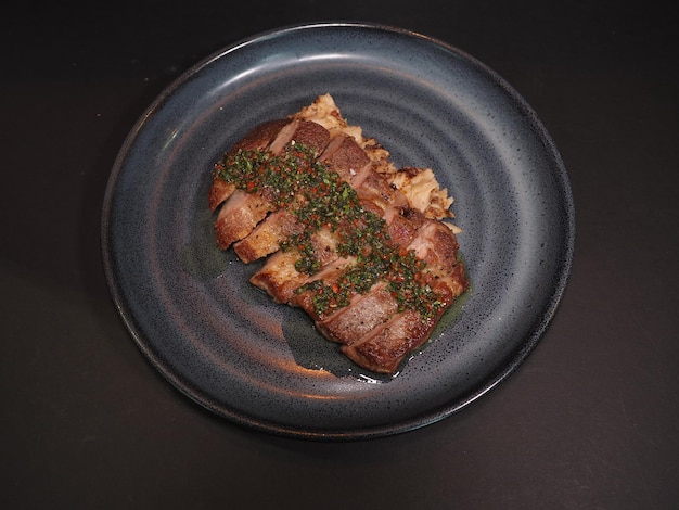 Iberico Pork Collar Steak with Chimichurri served in a dish isolated on dark background top view