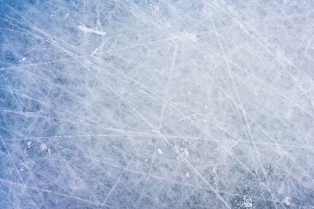 スケートやホッケーのマークと氷の背景、傷のあるリンクの表面の青いテクスチャ