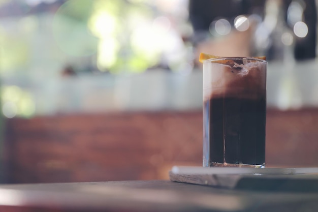 Ice black coffee with orange on wood background