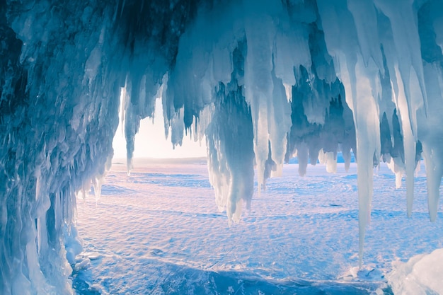 Ice cave with icicles on Baikal lake at sunset