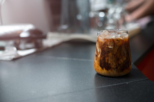 Ice coffee on a black table with cream being poured into it showing the texture