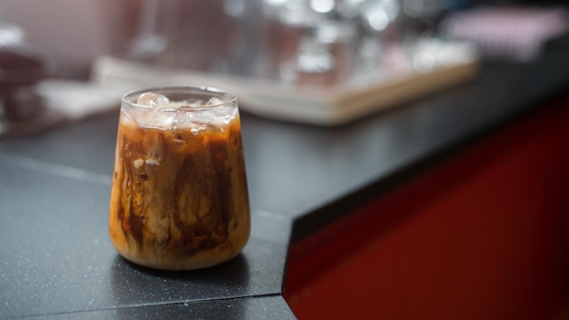 Ice coffee on a black table with cream being poured into it showing the texture