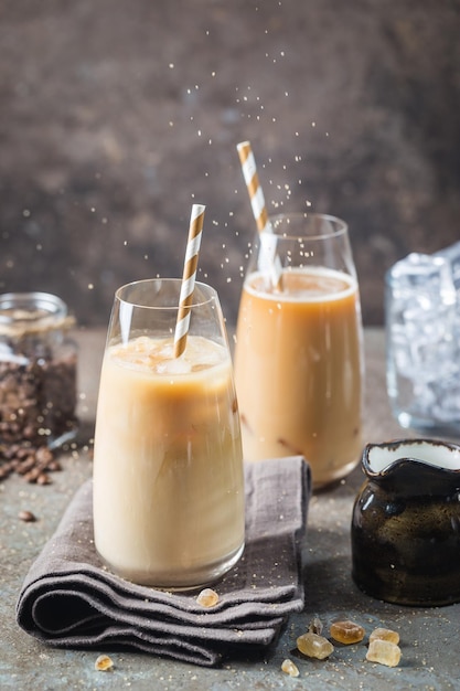 Ice coffee cold summer drink in a tall glass and coffee beans on a stone background.