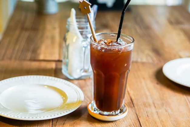 Ice coffee and a dish is placed on  a wooden table.