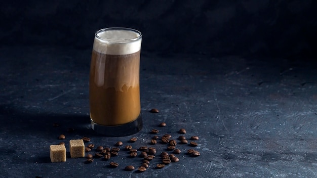 背の高いグラスにアイスコーヒーフラッペ。低いキーで暗い背景に涼しい夏の飲み物。牛乳の流れがコーヒーに注ぐ。