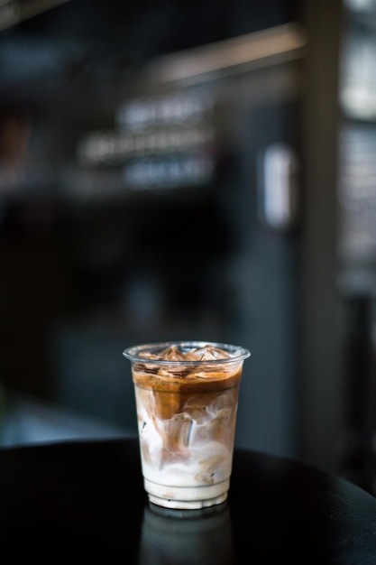 Ice coffee on a plastic cup with cream being poured into it showing the texture