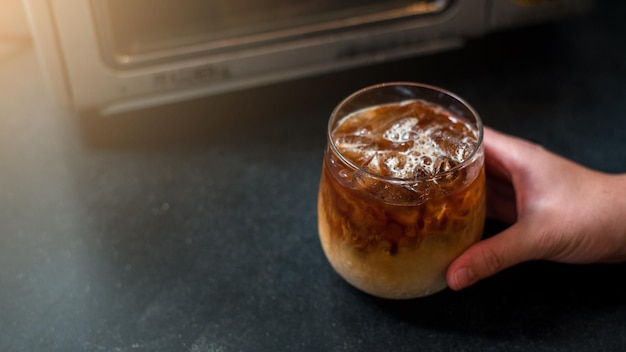 Ice coffee on a table with cream being poured into it showing the texture and refreshing look of the