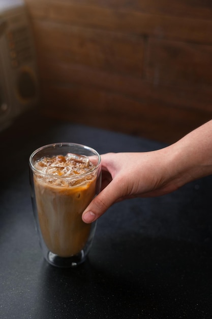 Ice coffee on a table with cream being poured into it showing the texture and refreshing look of the