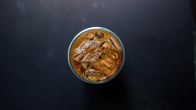 Ice coffee on a table with cream being poured into it showing the texture