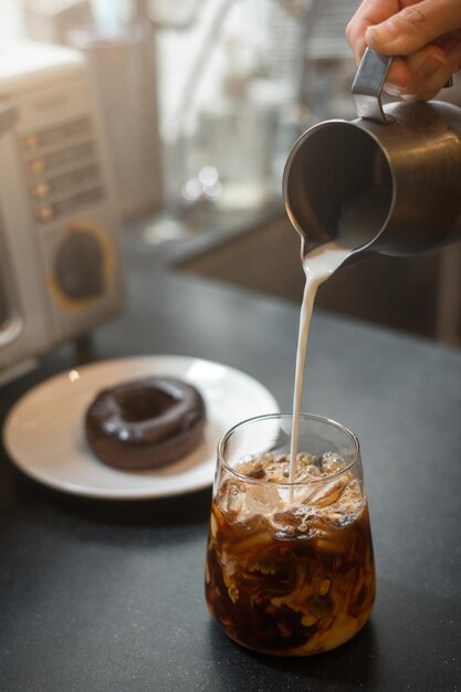 Ice coffee on a table with cream being poured into it showing the texture