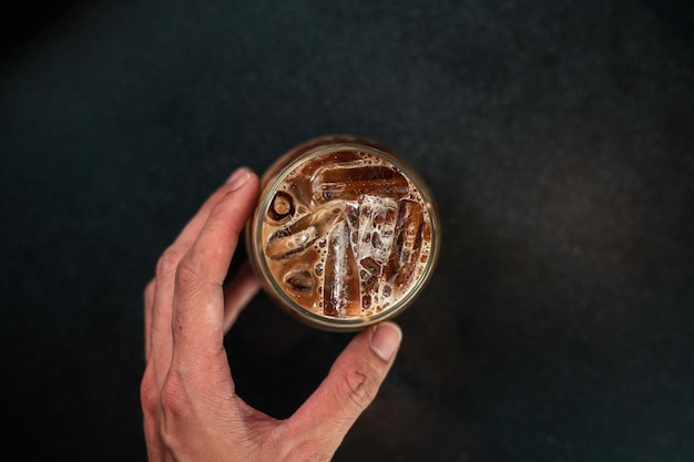 Ice coffee on a table with cream being poured into it showing the texture