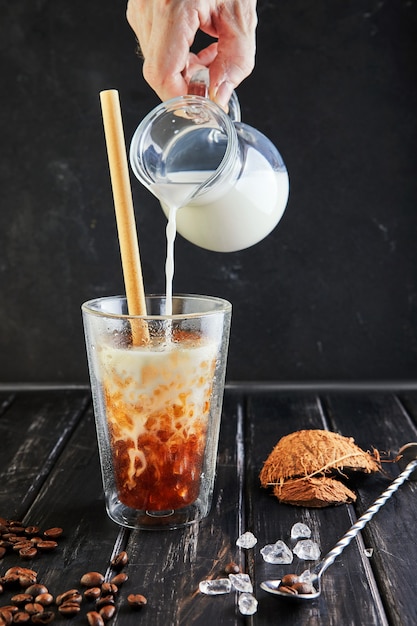 Ice coffee in Thai style with coconut milk and coffee beans on a black wooden