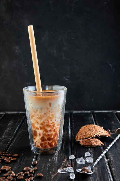 Caffè ghiacciato in stile tailandese con latte di cocco e chicchi di caffè su un legno nero