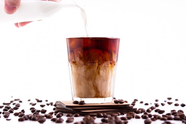 Ice coffee with cream poured over on white wall