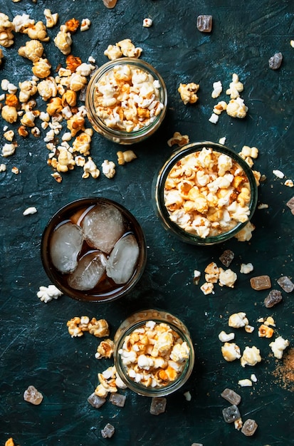 Ice cola and caramel popcorn unhealthy food and drink black table top view