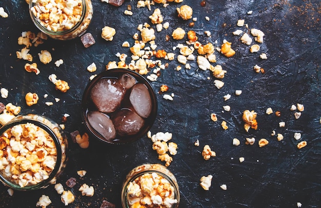 Ice cola and caramel popcorn unhealthy food and drink black table top view