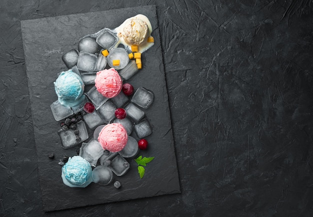 Ice cream balls of different types on ice on a black wall