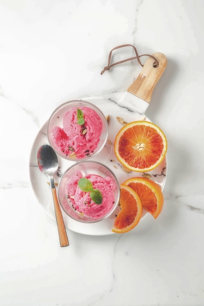 Photo ice cream, blood orange and cardamom sorbet, with fresh oranges and mint,  white marble , copyspace top view