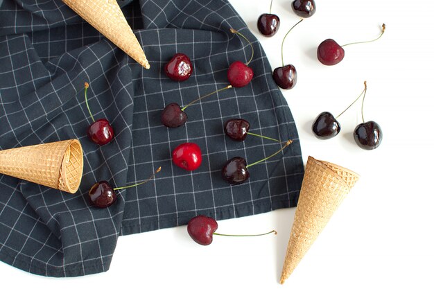 Ice cream concept Fresh cherries and waffle cone on checkered napkin 