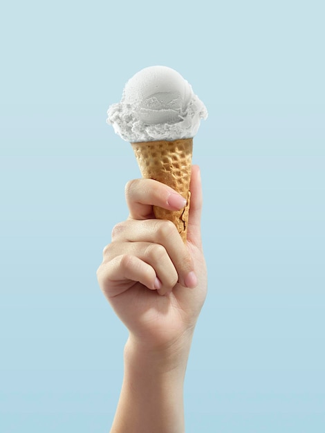 Ice cream cone on blue background woman holding ice cream by hand