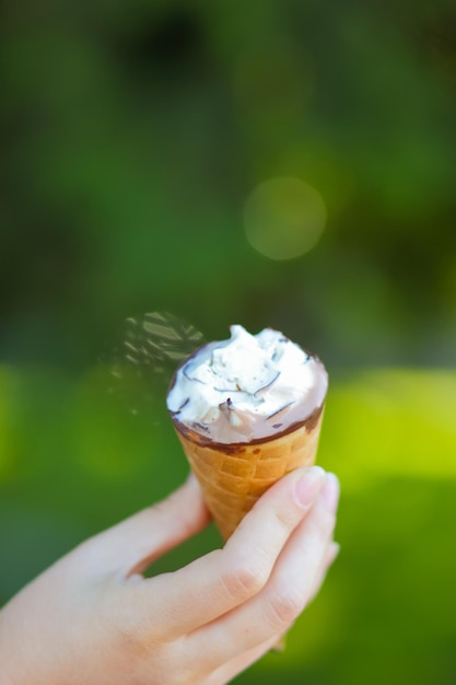 Ice cream cone in female hand Ice cream on sunny day on blurred background Sopy space