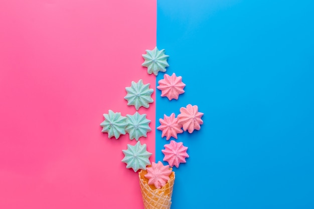 Ice cream cone with meringues on blue and pink