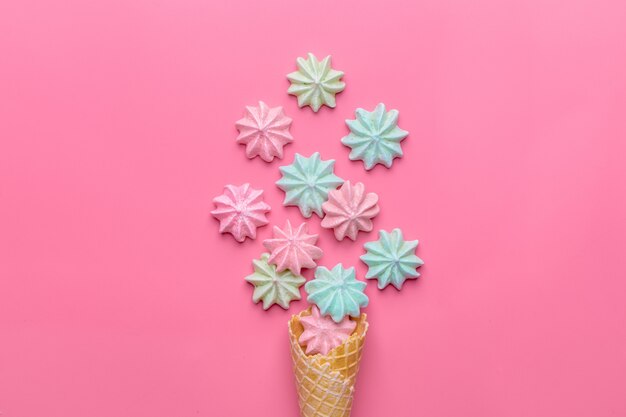 Ice cream cone with meringues on pink 