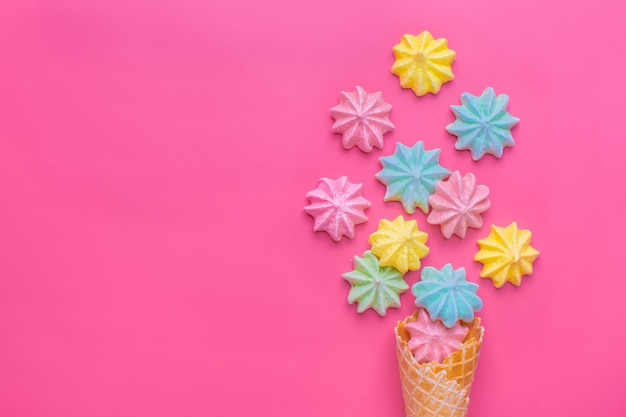 Ice cream cone with meringues on pink 