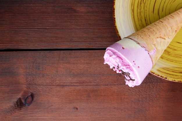 Ice cream cone on yellow plate Ice cream in waffle cup on dark wooden background Summer cold dessert Copy space