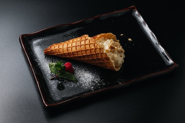 ice cream dessert in sugar cone  served on a black plate