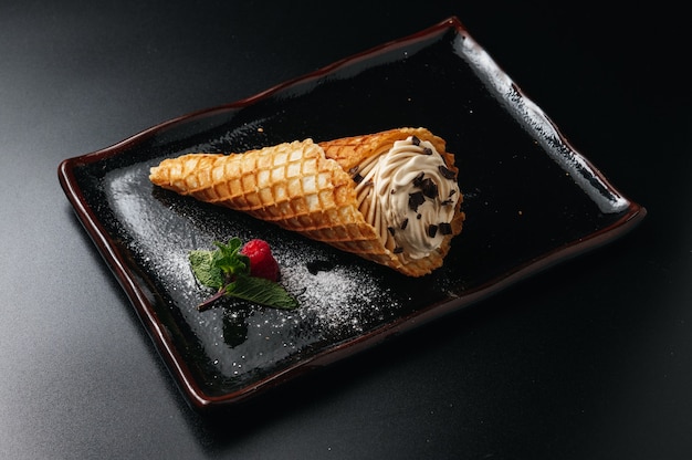 ice cream dessert in sugar cone  served on a black plate