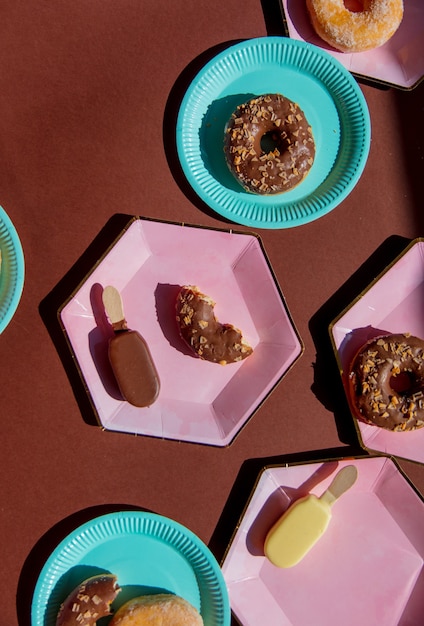 Gelato e ciambelle su piatti colorati su fondo marrone