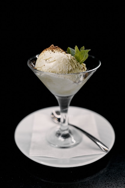 Ice cream in a glass on a plate with a dessert spoon