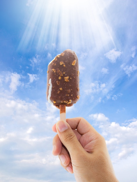 Ice Cream holded by hand on  sky background