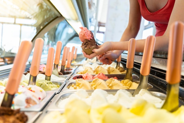 Ice cream showcase with a saleswoman preparing a tub with two flavors