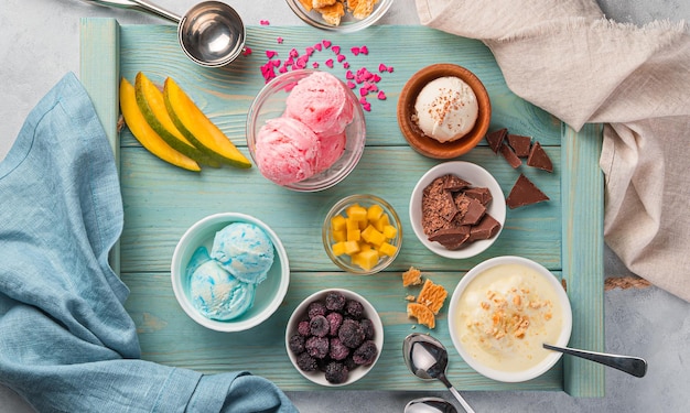 Ice cream of various types with fruits, berries and chocolate on a blue board. Summer dessert. Top view.