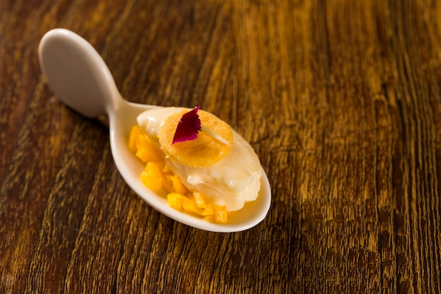 Ice cream with chopped mango and cornmeal in a spoon