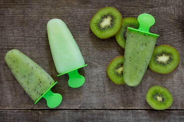 Ice cream with kiwi and fruit ice against a vintage wooden background, copy space.