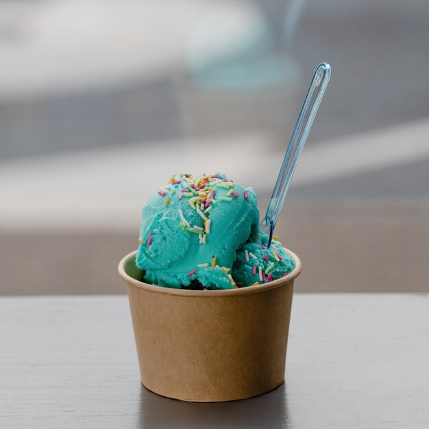 Ice cream with mint and sprinkling in paper cup on table in cafe