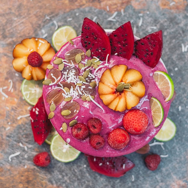 Gelato con pitaya rosa, fette di frutta drago rosso, fragola, lampone, lime, scaglie di cocco, semi di zucca